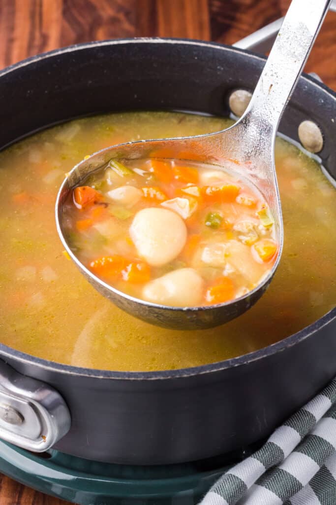 Butter beans being ladled from a black saucepan.